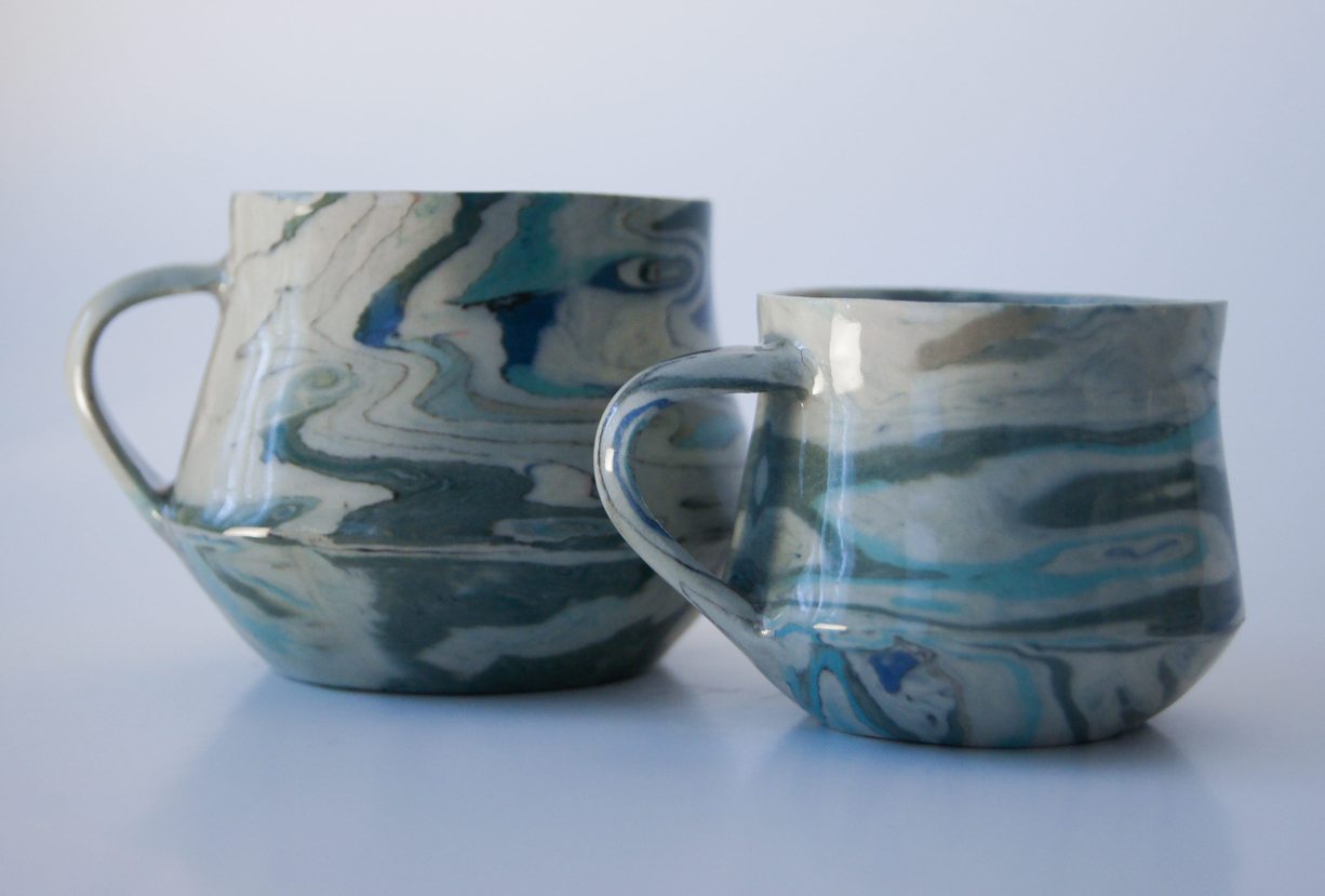 Photo of artistic ceramic mugs in blues and greens