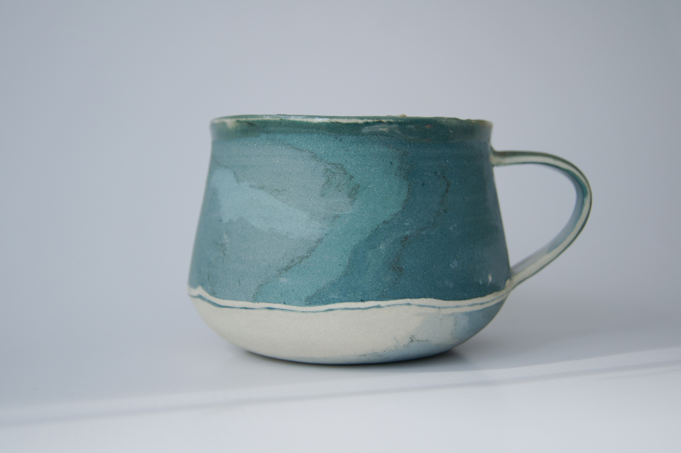 Photo of artistic ceramic mug in blues and greens