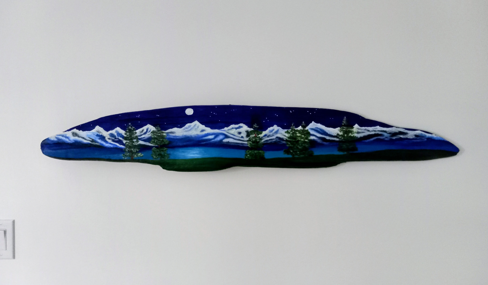 Painting on driftwood showing nighttime scene of mountains and water