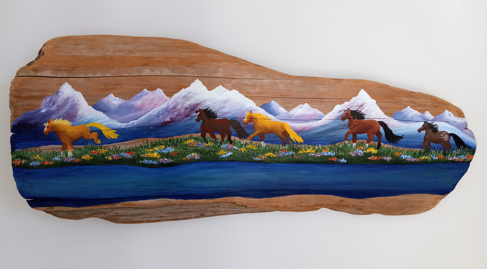 Painting on driftwood showing horses running in front of mountains